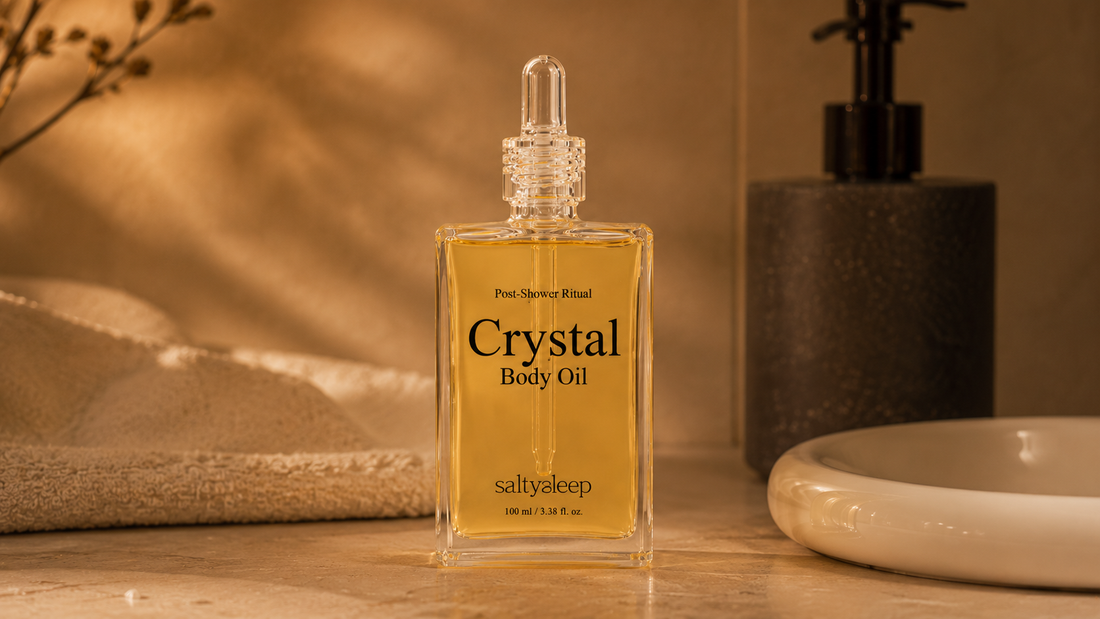 A Crystal Body Oil bottle on a warm bathroom counter, a clean product still life.